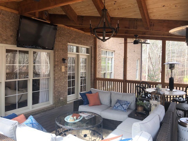 enclosed back porch featuring wrap-around couches and a mounted TV screen