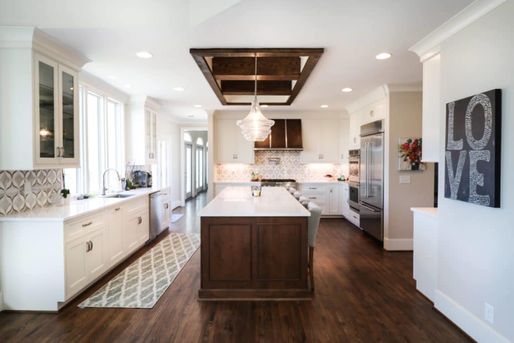 custom modern kitchen with white countertops, overhead hanging lights, and white countertop island